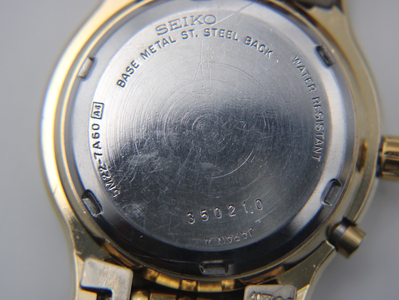 Close-up of the watch's stainless steel case back, showing the model number 5M22-7A60, serial number 350210, and 'water resistant' engraving.