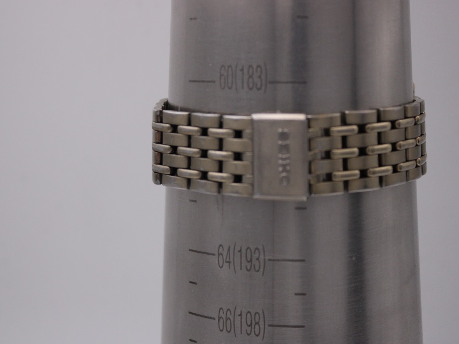 The watch bracelet on a wrist sizing gauge, showing the internal circumference of 183mm (18.3cm) with the signed Seiko clasp closed.