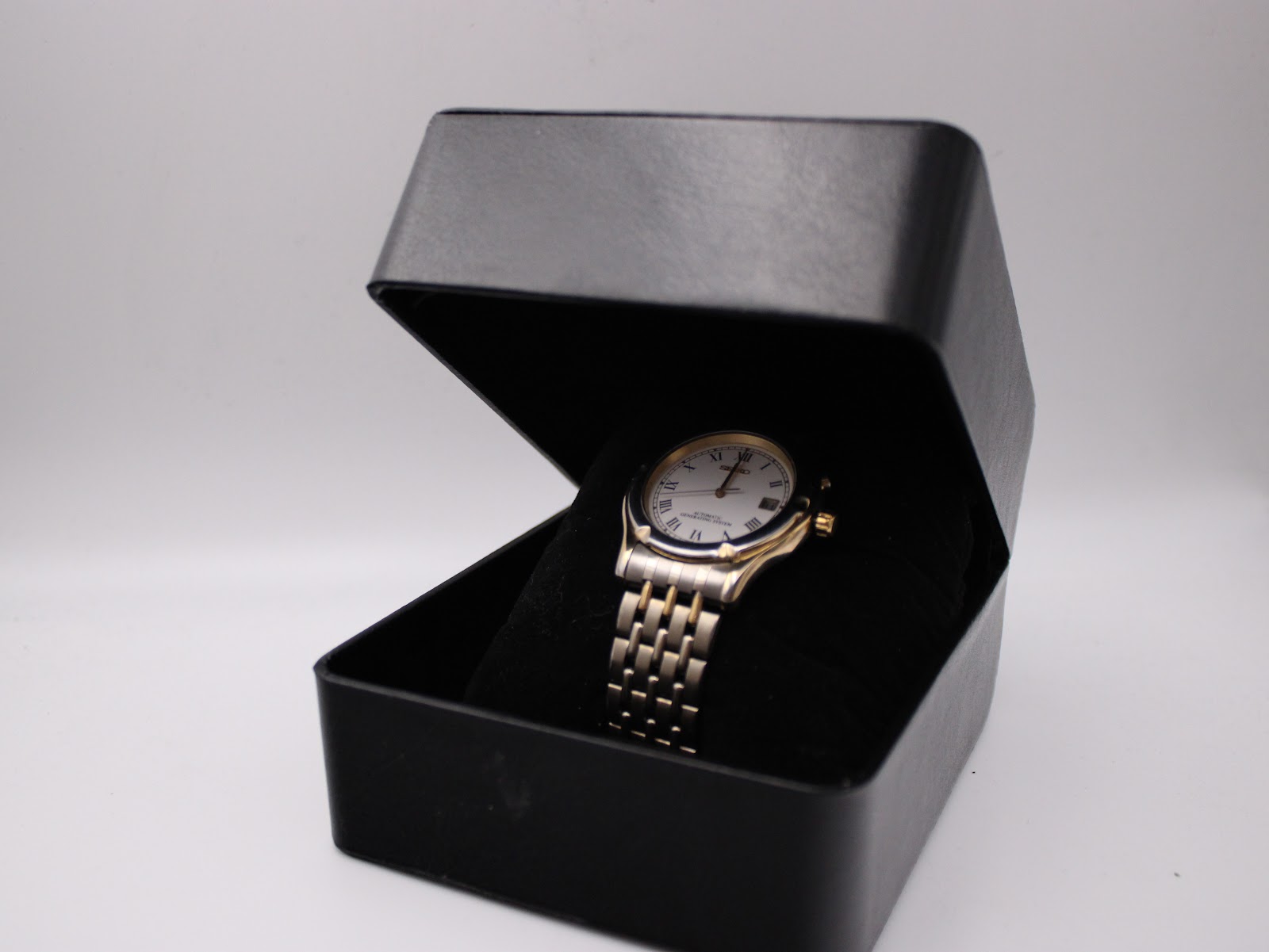 The Seiko watch displayed within a generic black presentation box, resting on a velvet cushion.