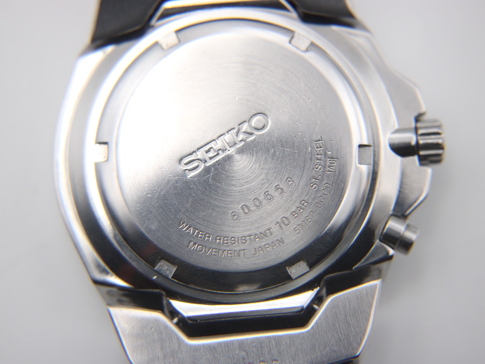 Close-up of the brushed stainless steel case back with Seiko branding, serial number 8D0658, and water resistance rating.