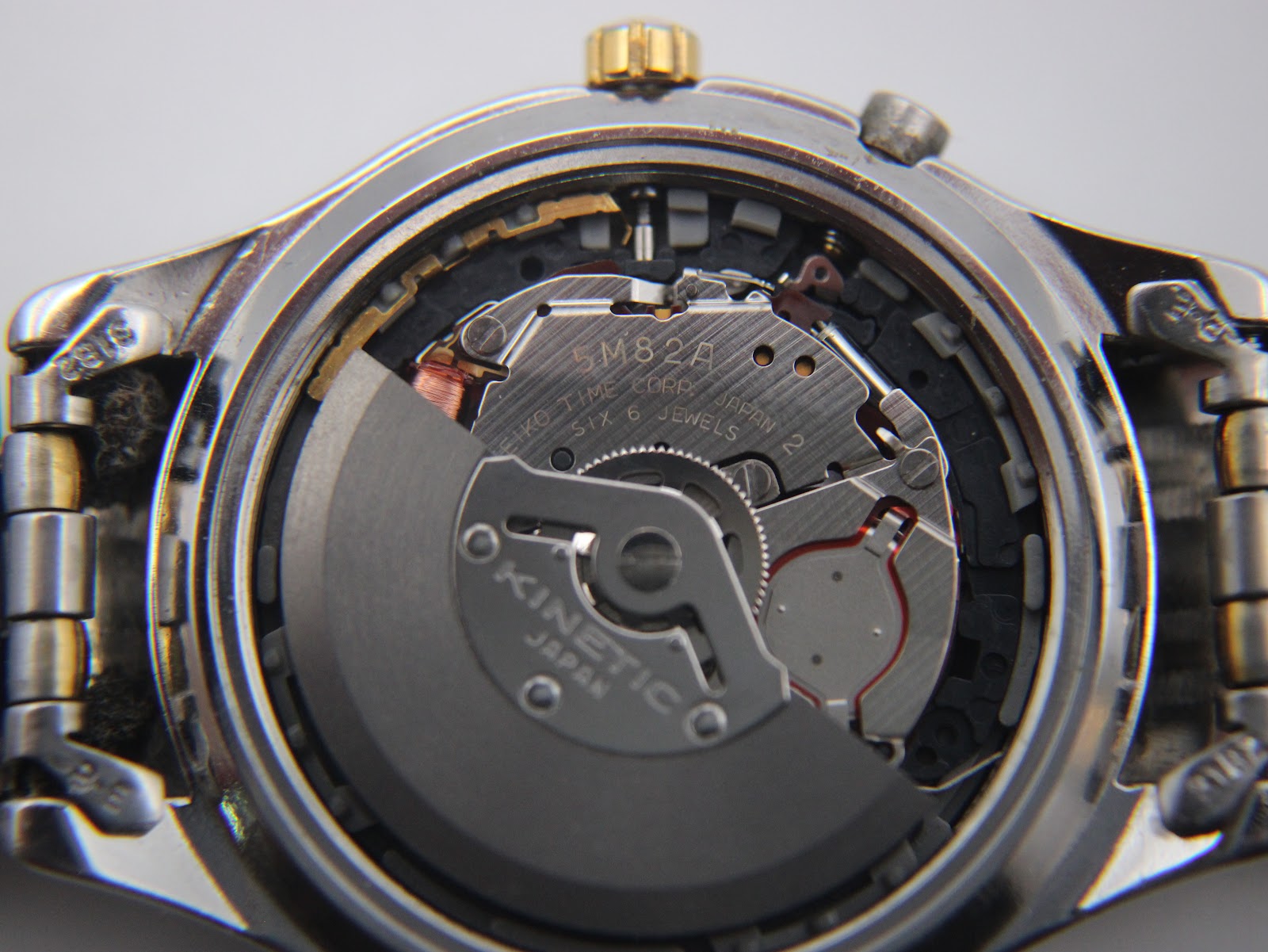 Close-up view of the Seiko 5M82A Kinetic movement inside the open case, showing the rotor and internal mechanics.