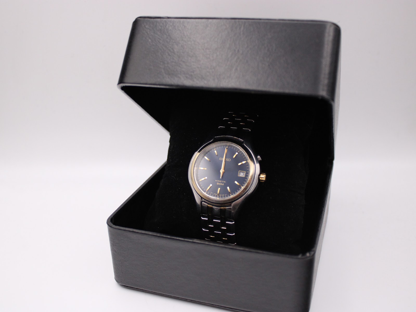 Seiko Kinetic watch displayed inside a generic black presentation box, angled shot.