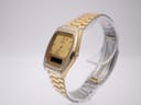 Angled side view of the SEIKO H448-5000 watch, showing the gold-plated case and bracelet on a stand.