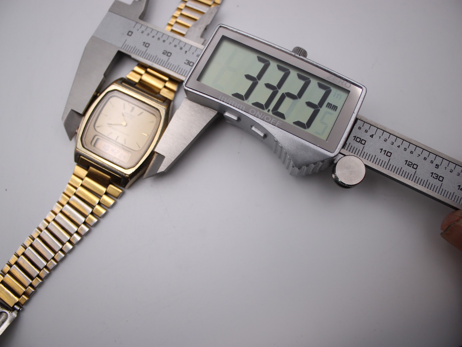 Digital caliper measuring the case width of the watch, showing a precise reading of 33.23mm.