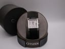 Front view of Citizen Eco-Drive watch in its open circular original box, with the lid alongside.