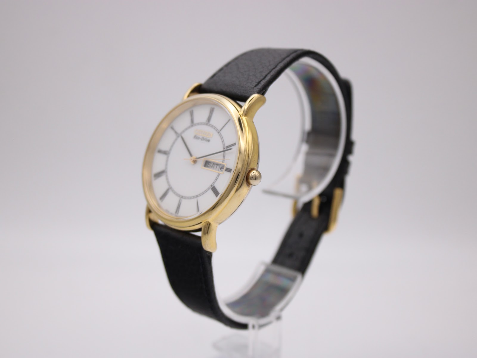 Angled side view of the Citizen Eco-Drive watch on a stand, highlighting the polished gold case and crown.