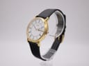 Angled side view of the Citizen Eco-Drive watch on a stand, highlighting the polished gold case and crown.