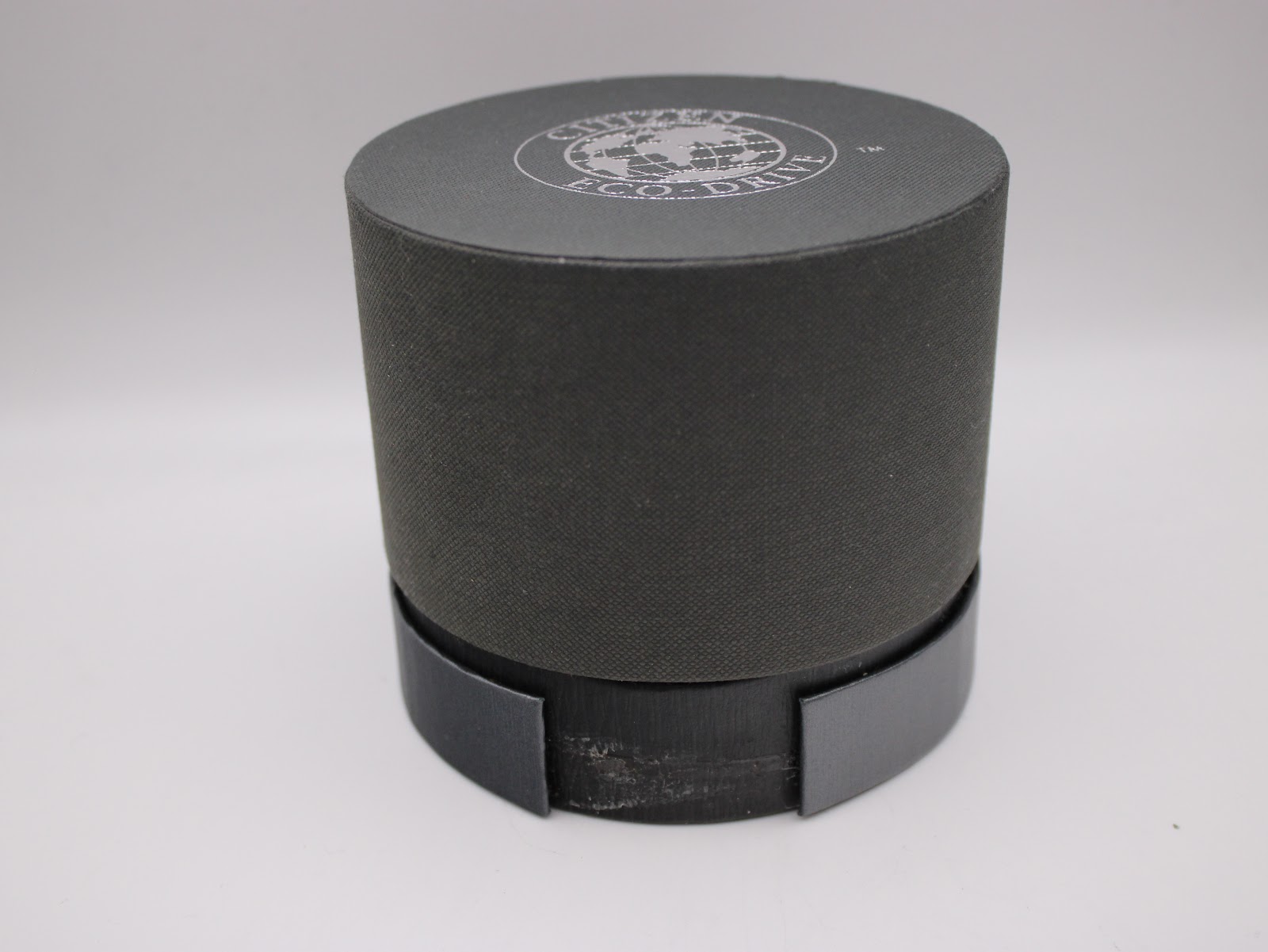 Closed view of the dark grey cylindrical Citizen Eco-Drive watch box.