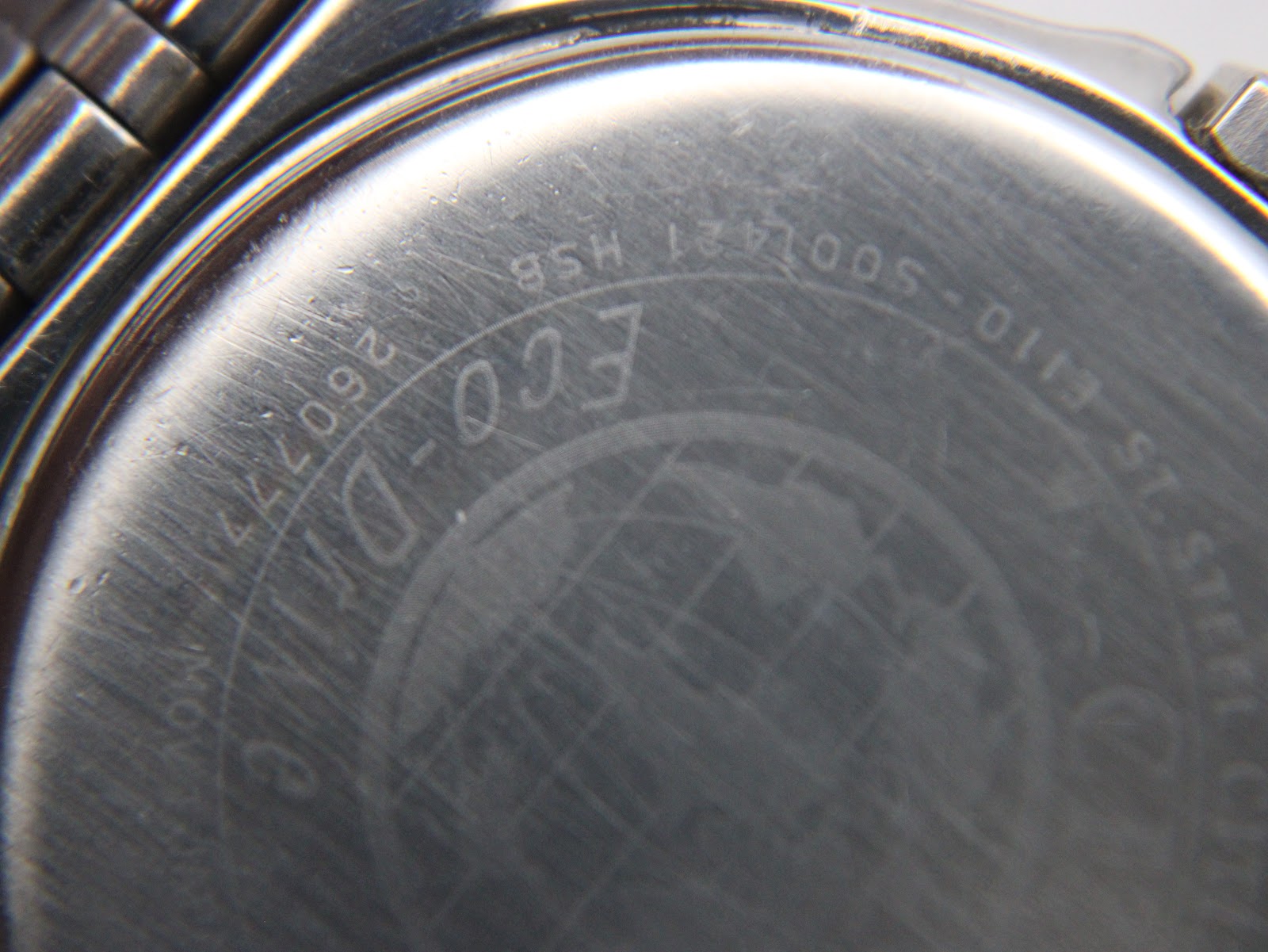 Extreme close-up of the Citizen watch case back, revealing the serial number 'E110-S001421 HSB 260772'.