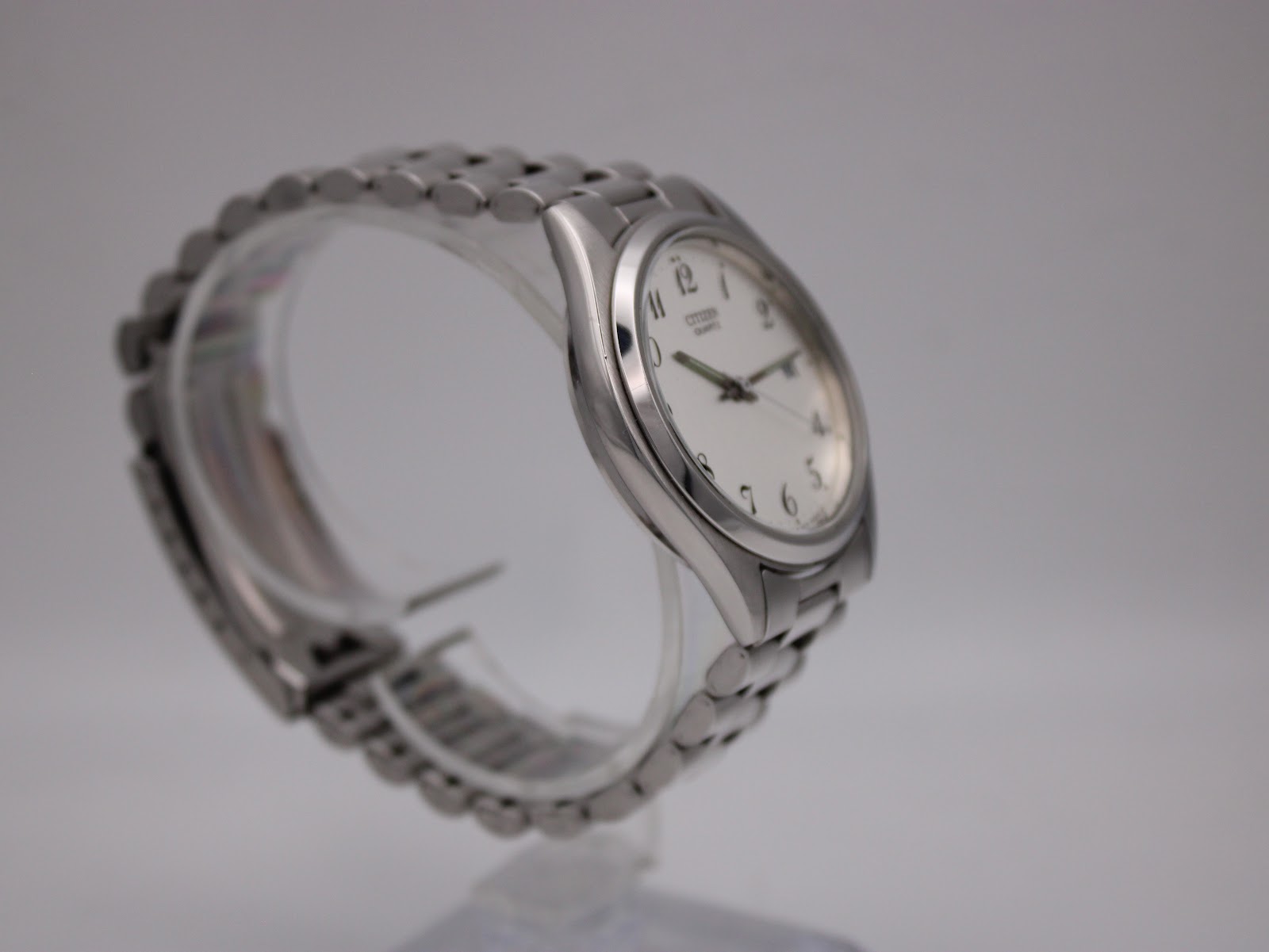 Angled side view of the Citizen watch on a display stand, highlighting the stainless steel bracelet and case profile.