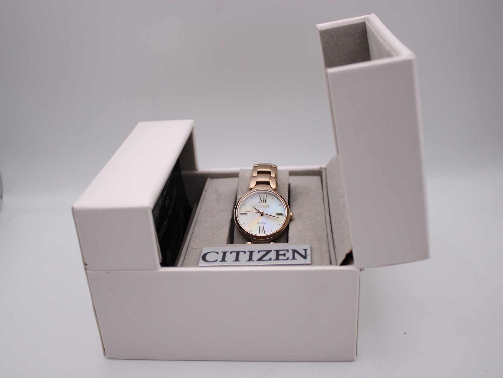 Citizen Eco-Drive watch in its open original white box, showing the rose gold tone watch inside.