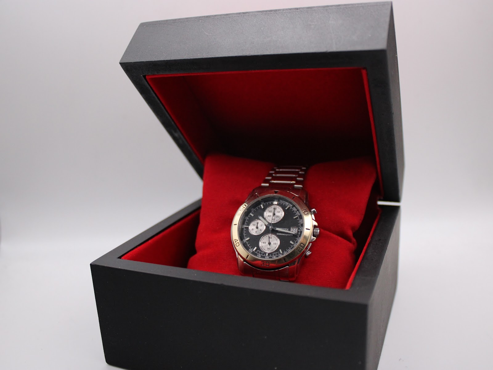 Citizen two-tone chronograph watch displayed in its open original black box with red interior.