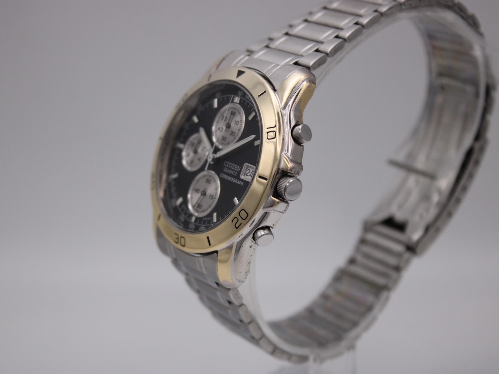 Angled side view of the Citizen watch showing the crown, pushers, and integrated bracelet.