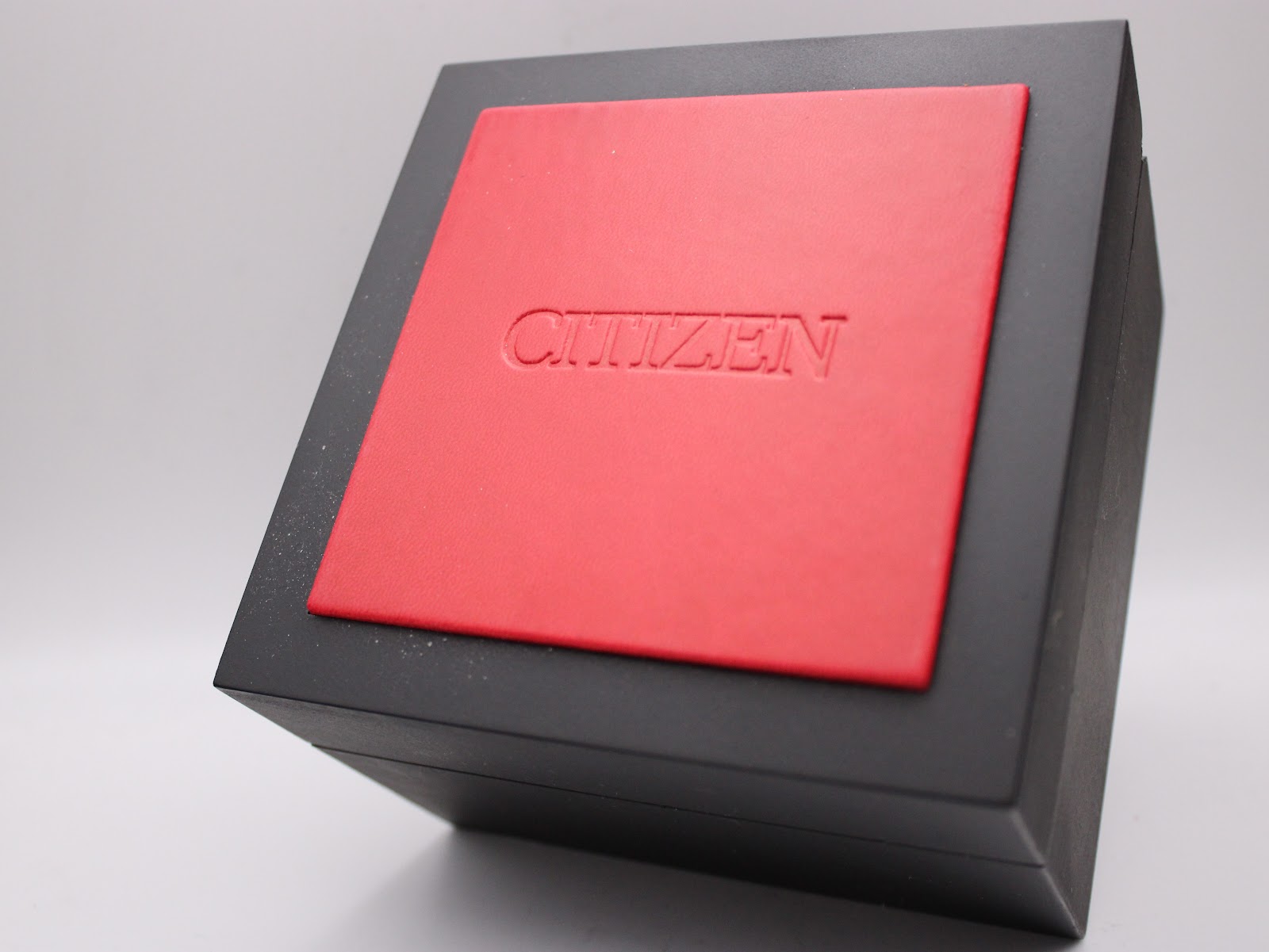 Top view of the closed original black Citizen watch box with an embossed red central panel.