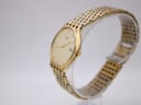 Angled side view of the Citizen gold tone watch on a clear display stand, showing the case profile and bracelet links.