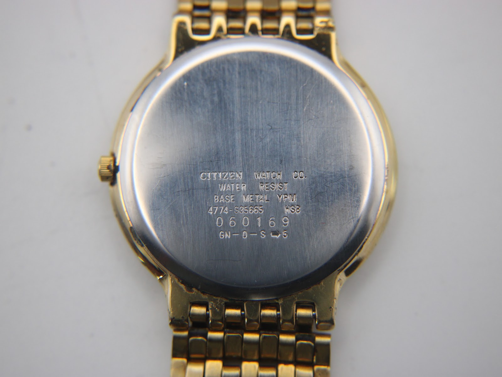 Close-up of the brushed stainless steel case back of the Citizen watch, showing model and serial numbers.