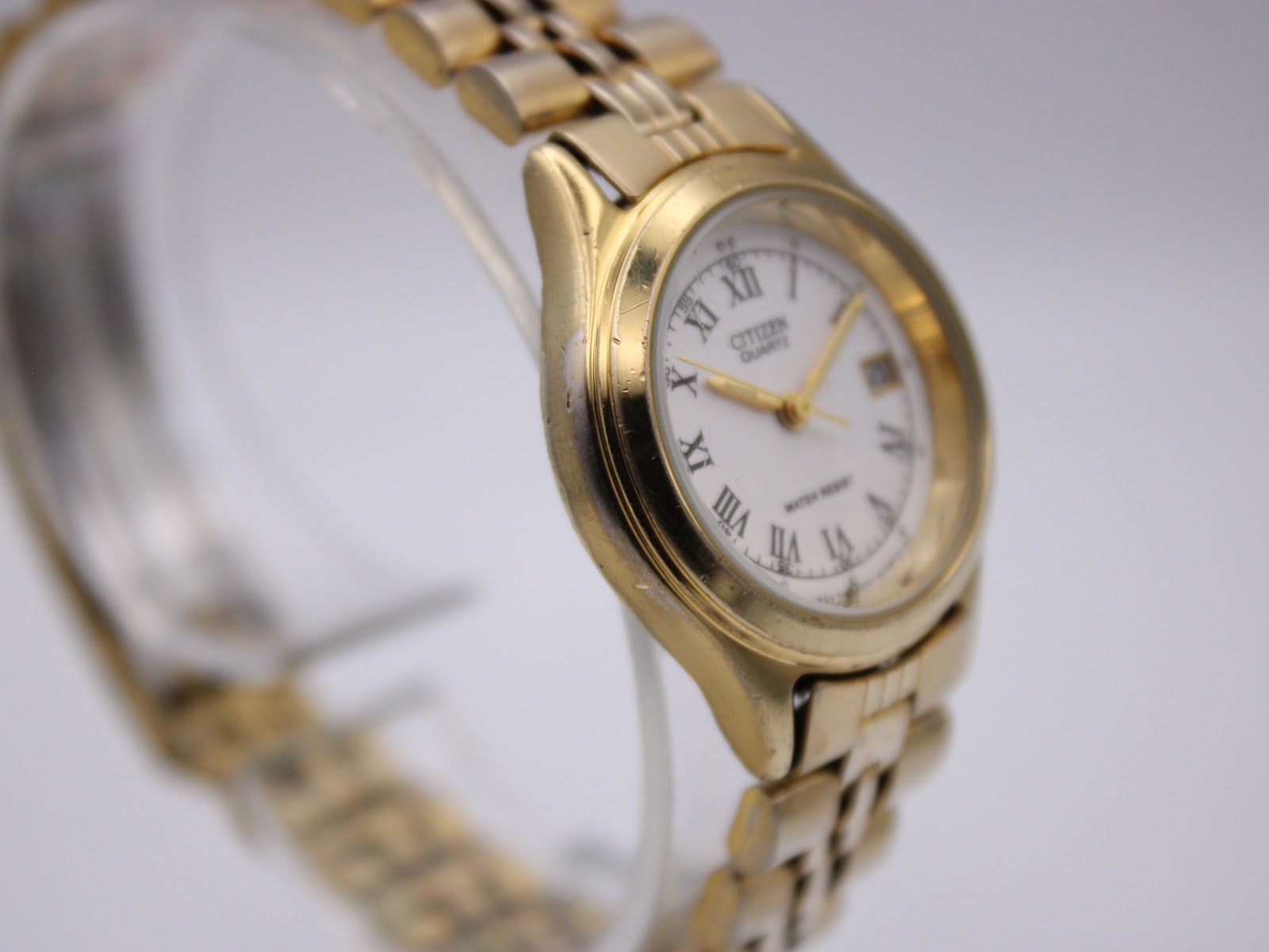 Close-up side view of the Citizen watch, highlighting some wear on the gold-tone case near the lugs.