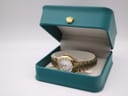 The Citizen watch resting inside its original teal-coloured Citizen watch box with a gold crown emblem.