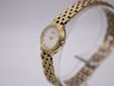 Angled view of the gold tone Citizen watch showing the case and bracelet on a clear display stand.