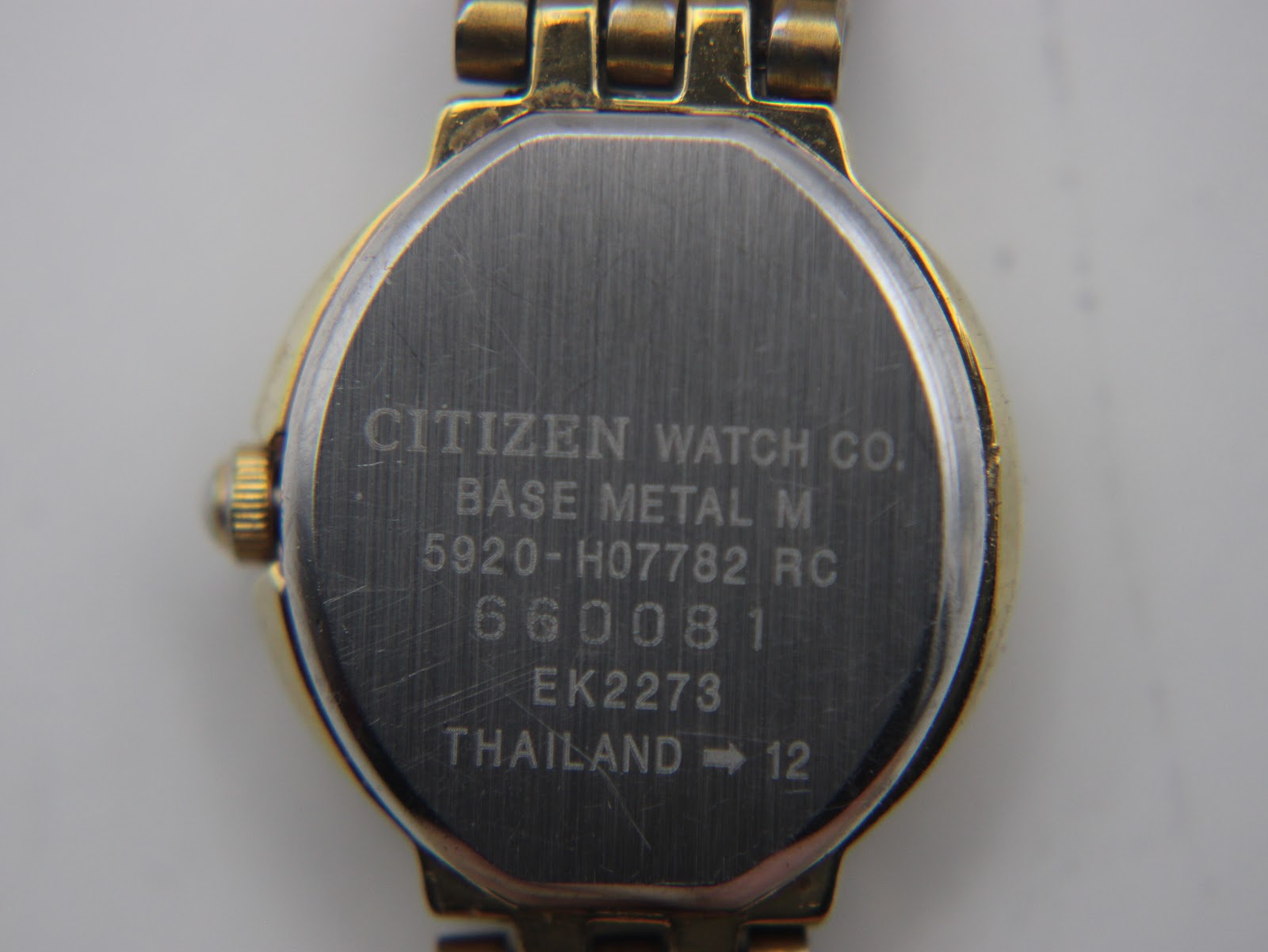 Close-up of the watch case back, showing 'CITIZEN WATCH CO. BASE METAL M 5920-H07782 RC 660081 EK2273 THAILAND -> 12' engravings.