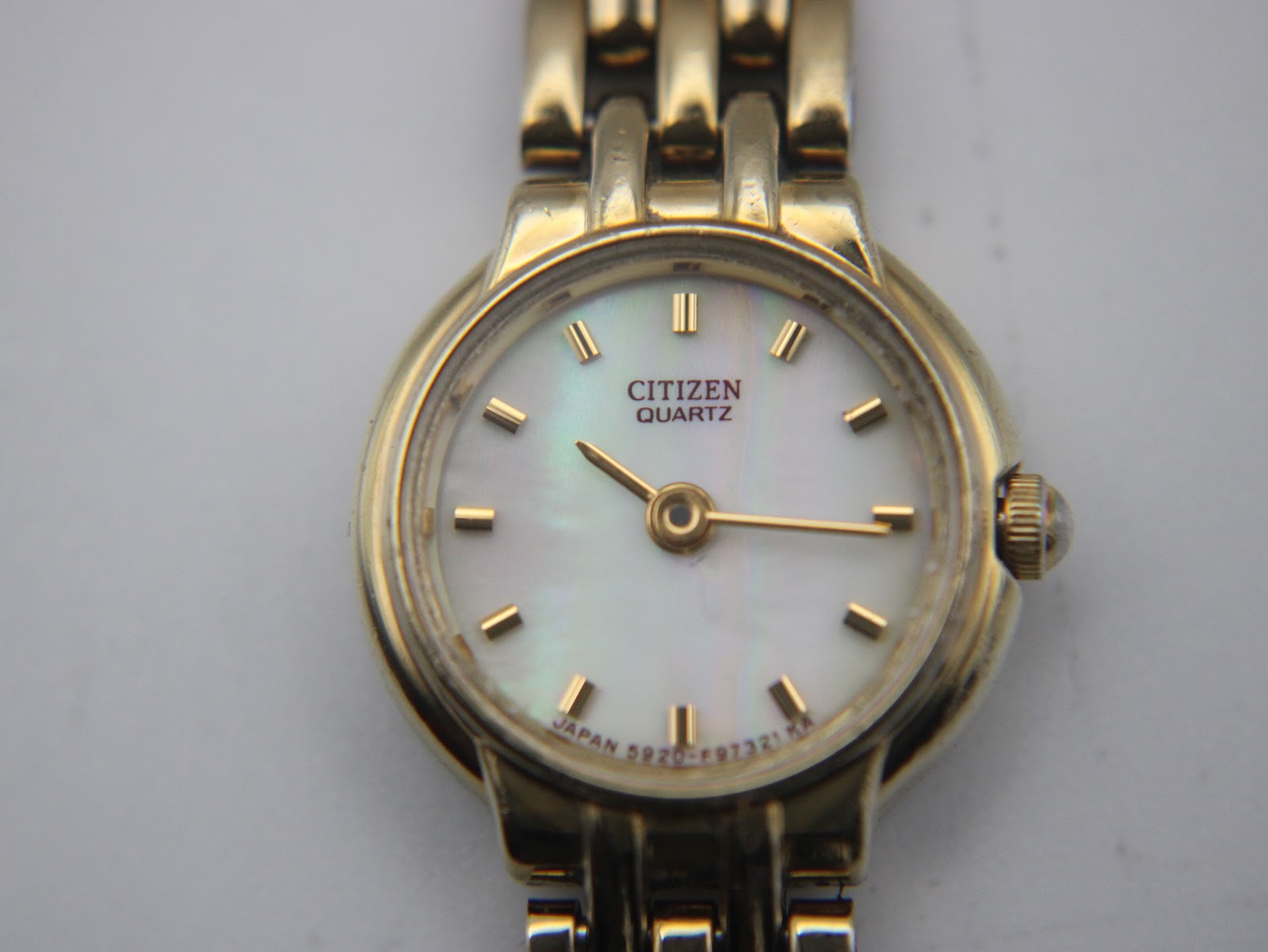 Detailed close-up of the Citizen watch dial, featuring gold baton indices and 'CITIZEN QUARTZ' text.