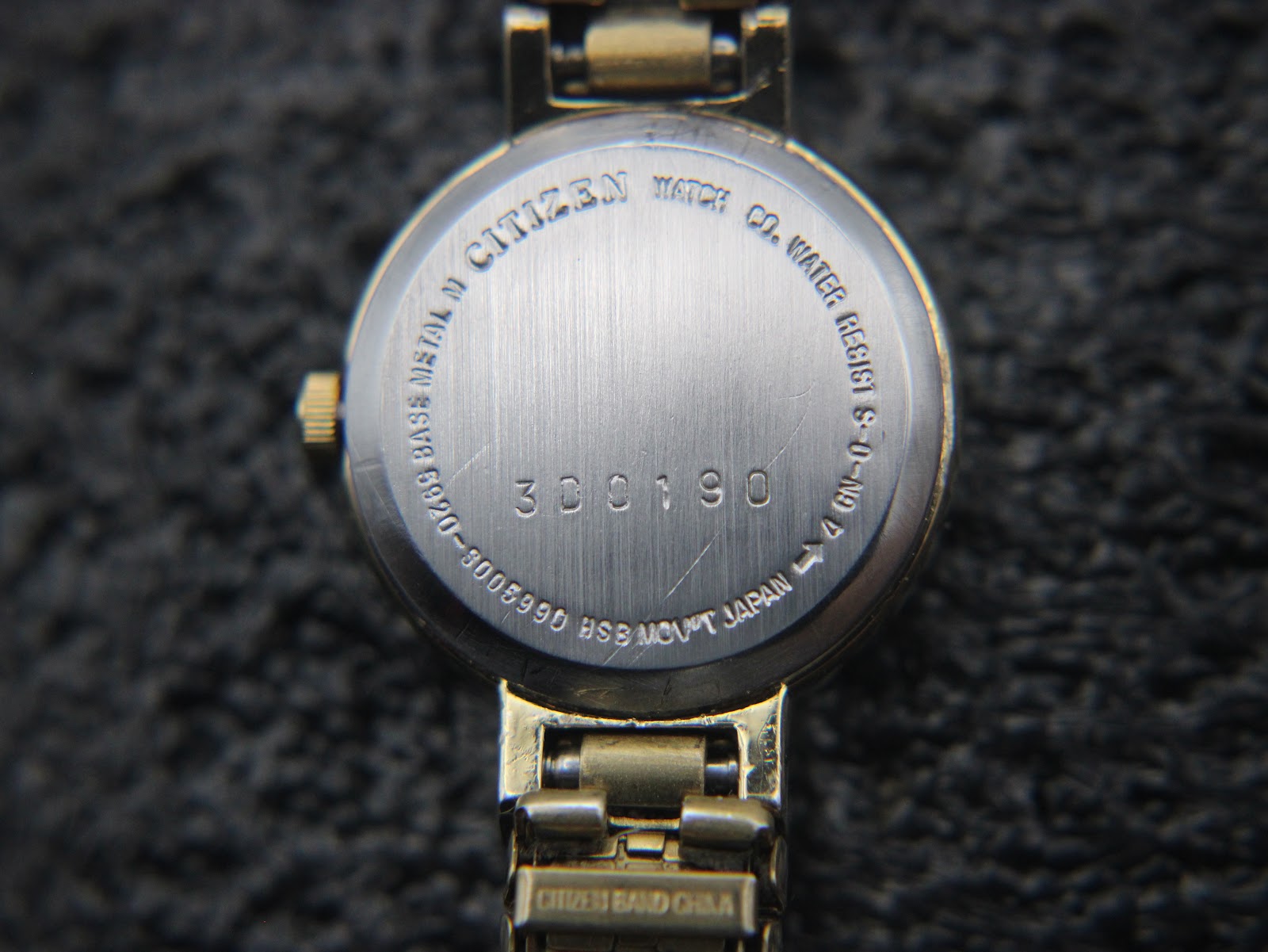 Detailed close-up of the brushed stainless steel case back of the Citizen watch, showing 'CITIZEN WATCH CO. WATER RESIST BASE METAL N 3005990 300190 BSM MOV'T JAPAN'.