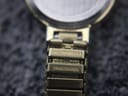Macro shot of the underside of the gold tone expansion bracelet links, clearly showing 'CITIZEN BAND CHINA' and 'STAINLESS STEEL' engravings.