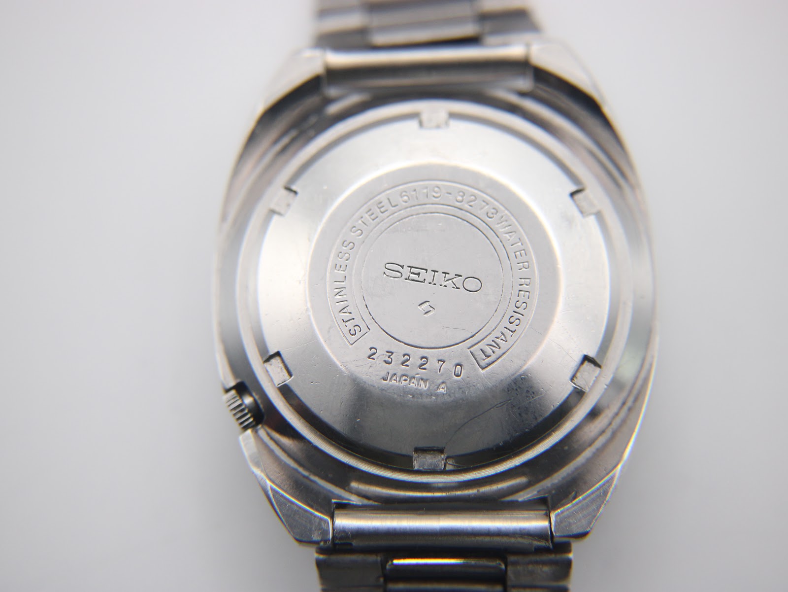 Close-up of the stainless steel case back of the Seiko 6119-8273, displaying model 6119-8273, serial number 232270, and 'Water Resistant Japan A' engravings.