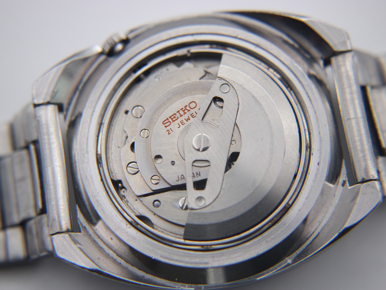 Close-up of the watch with the case back removed, partially revealing the Seiko 21-jewel automatic movement.
