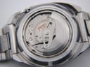 Close-up of the watch with the case back removed, partially revealing the Seiko 21-jewel automatic movement.