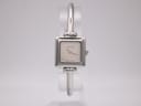 Front view of Gucci 1900 L watch with square silver case and minimalist silver dial on a display stand.