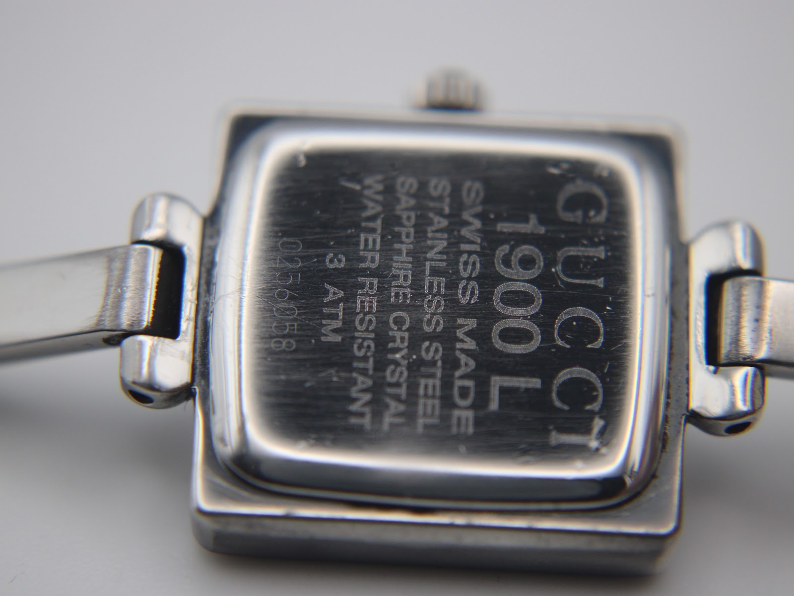 Close-up of the polished stainless steel case back of the Gucci 1900 L, showing model number, serial, and water resistance.