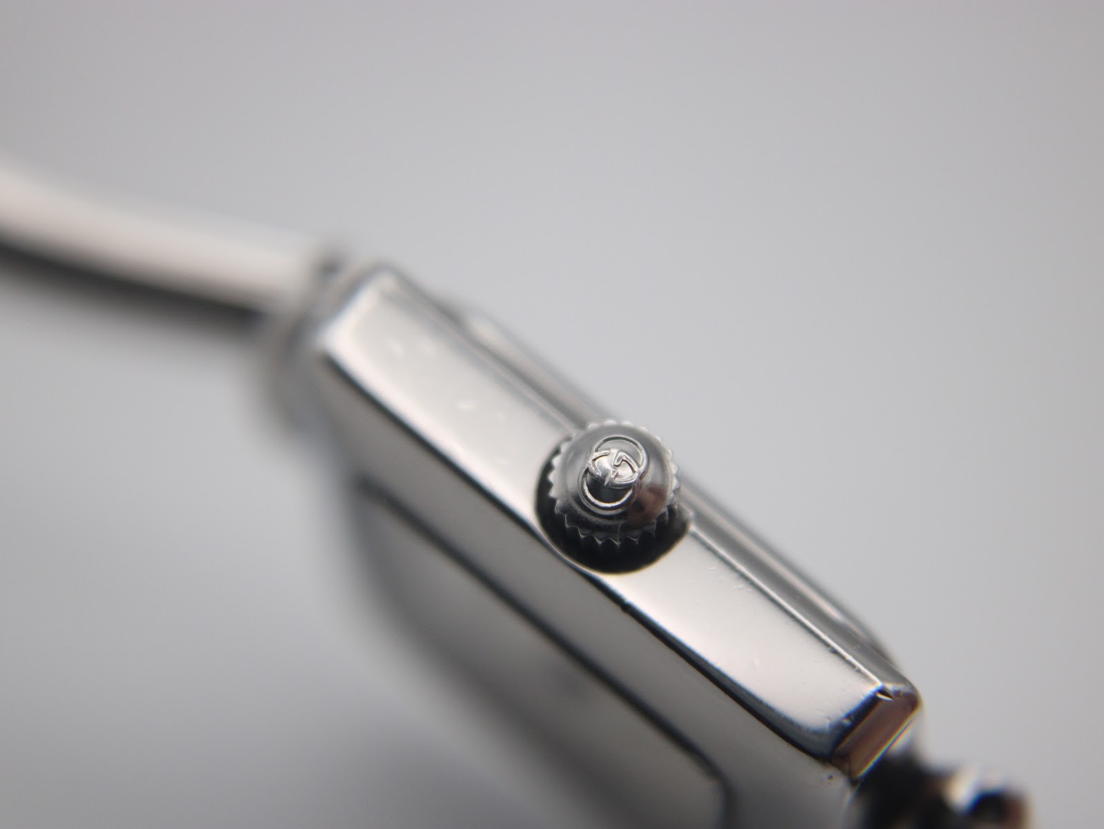 Close-up of the watch crown, showing the embossed Gucci logo.