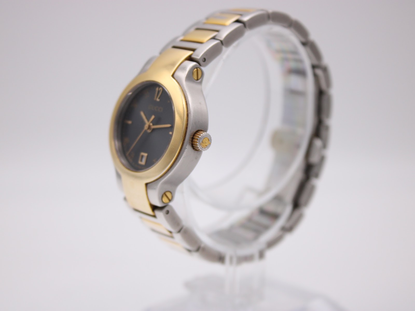 Angled side view of the Gucci 8900L watch on a stand, showing the two-tone case and crown.
