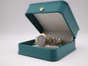 The Gucci 8900L watch resting inside its original teal-coloured presentation box with a gold-tone crown detail.