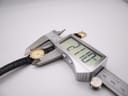 Close-up of a digital caliper measuring the Tissot watch case diameter at 21.10mm, with the strap visible.