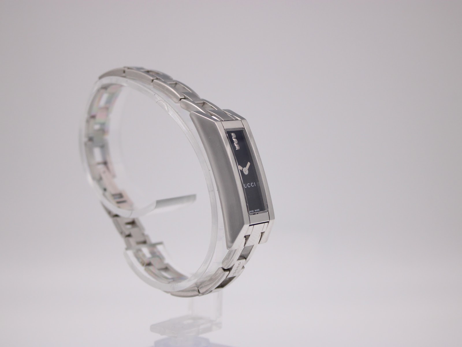 Angled view of the Gucci 110 watch on a display stand, showing the integrated bracelet.