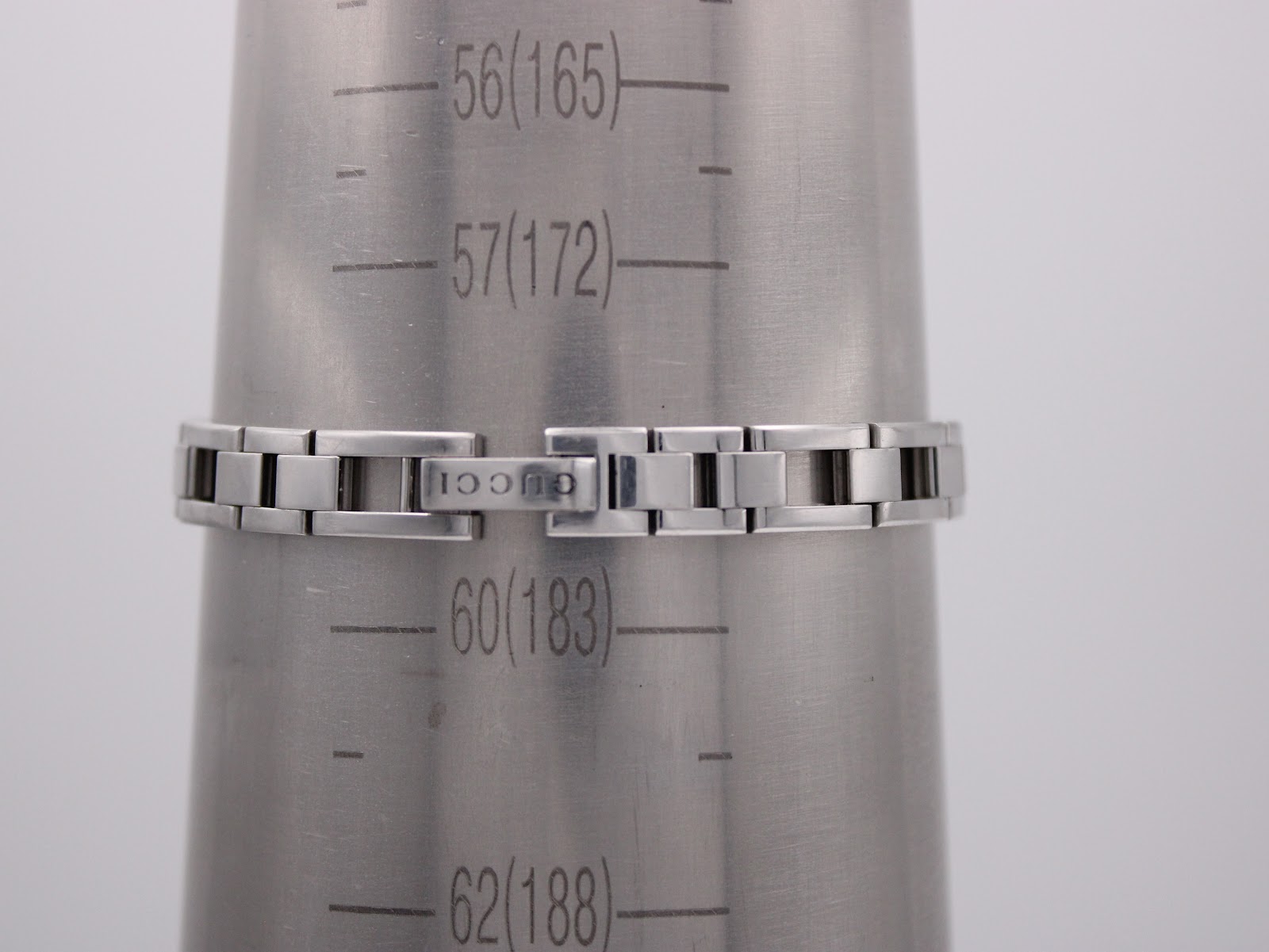 The integrated stainless steel bracelet of the Gucci 110 watch on a wrist sizing cone, showing a circumference of approximately 172mm.