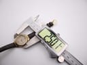 Digital caliper measuring the case diameter of the Citizen Eco-Drive watch, showing a precise measurement of 28.01mm.