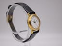 Angled left-side view of the Tissot C 212 watch on a display stand, showcasing the side profile of the gold-tone case and black leather strap.