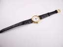 Full view of the Tissot C 212 watch lying flat, showing the black leather strap with its gold-tone pin buckle.