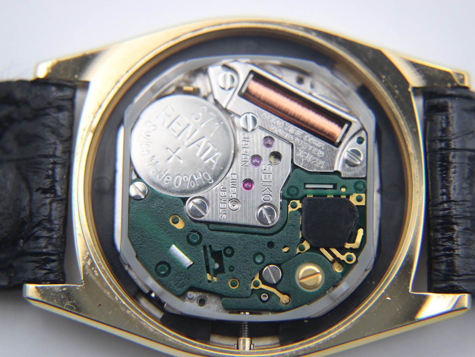 Detailed view of the Seiko quartz movement inside the watch case, showing the battery and internal components.