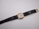 Overhead view of the Seiko watch laid flat, displaying the full black leather strap with its gold-tone buckle.