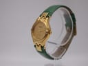 Angled view of the Tissot Stylist watch on a display stand, highlighting the curved gold-tone case and green leather strap.