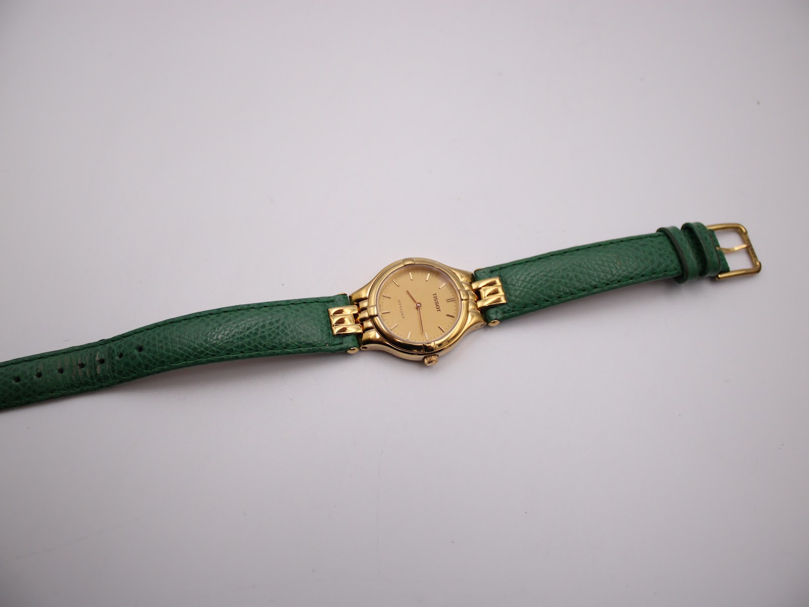 Overhead view of the Tissot Stylist watch laid flat, displaying the full length of the green leather strap.