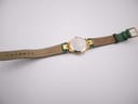 Back view of the Tissot Stylist watch laid flat, showing the case back and the underside of the green leather strap.