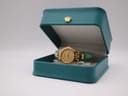 The Tissot Stylist watch resting inside its original teal-coloured presentation box, which features a gold crown emblem.