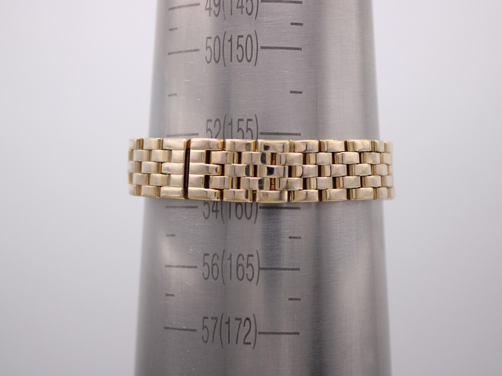 The gold-tone bracelet of the watch displayed on a wrist sizing gauge, showing a circumference measurement around 158-160mm.
