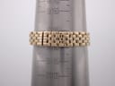 The gold-tone bracelet of the watch displayed on a wrist sizing gauge, showing a circumference measurement around 158-160mm.