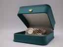 The Raymond Weil 5889 watch placed inside an open teal green presentation box with a gold crown emblem.